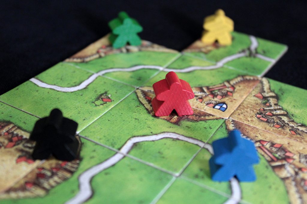 Closeup photo of meeples and squares from the boardgame Carcassonne.