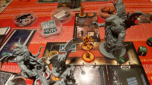 A game of Cthulhu: Death May Die in action. Shows a number of room tiles with investigator figures, a minature of Cthulhu and several monsters, dice, and various tokens in bowls and on the board.