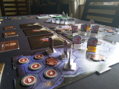 A game of Gloomhaven in progress. Many standees, tokens, cards, and room tiles.