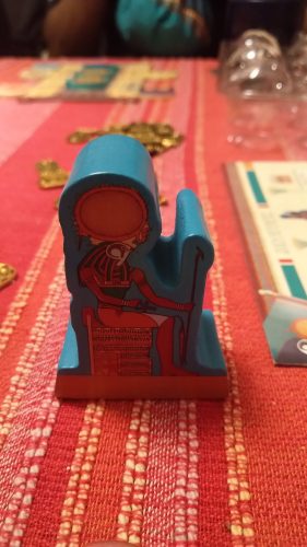The first player token of Ra, a large wooden meeple showing the Egyptian god Horus.